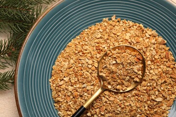 Plate with dried orange seasoning zest on beige textured table, top view