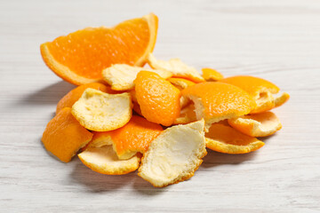 Fototapeta na wymiar Orange peels preparing for drying and piece of fresh fruit on white wooden table, closeup