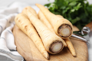 Raw parsley roots and peeler on table, closeup