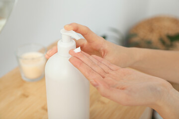 Woman applying body cream on hand in room, closeup