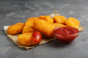 Tasty chicken nuggets with ketchup on grey table