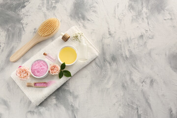 Flat lay composition with pink sea salt, flowers and different spa products on textured table. Space for text