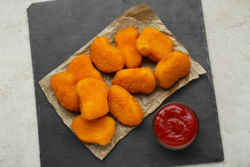 Tasty chicken nuggets with ketchup on light grey textured table, top view