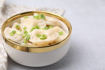 Cooked dumplings (varenyky) with tasty filling and green onion on light table, closeup