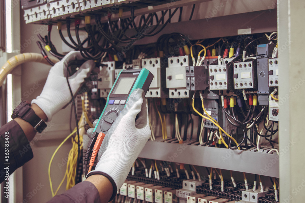 Wall mural electrician engineer tests electrical installations and wires on relay protection system.