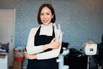 Portrait of a young asian female hairdresser holding qualified haircut tools in her salon for a...