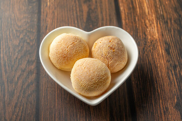 cheese bread in heart-shaped container on wooden table
