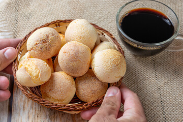 man serves cheese bread on wooden table, traditional brazilian meal concept with typical food