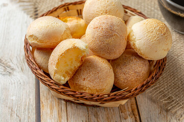 cheese breads in wooden basket with cup of coffee, concept of traditional brazilian meal, afternoon snack