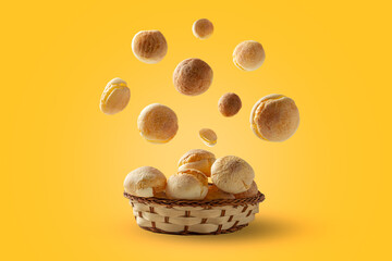 cheese breads falling into wooden basket, Brazilian traditional food concept on yellow background