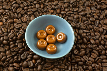 Coffee hard candy in small blue dessert bowl and roasted coffee beans