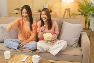 Obraz na płótnie Canvas Lifestyle at home concept, LGBT lesbian couple eats popcorn and switch channel while watching movie