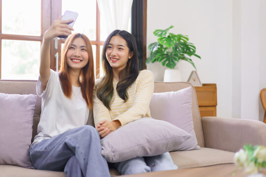 Activity at home concept, LGBT lesbian couple smiling and using smartphone to selfie together