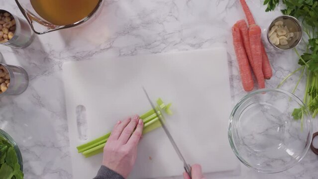 Curring vegetables on a white cutting board to cook vegetarian white bean soup.