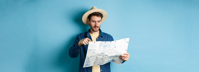 Handsome guy choosing place to go, pointing at sighseeing map on vacation, travelling on summer...