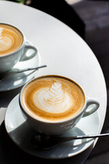Top view of hot two cup of coffee with latte art in white cup and spoon.