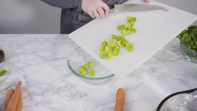 Curring vegetables on a white cutting board to cook vegetarian white bean soup.