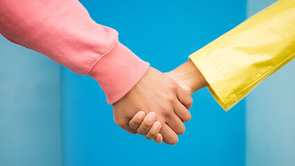 Couple, love and holding hands together for support care, relationship and bonding in blue background studio. Man, woman and hand for partnership, romance trust and solidarity or compassion lifestyle