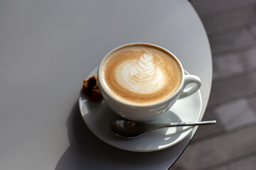 Top view of hot coffee with latte art in white cup and spoon.