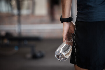 Water bottle, fitness and gym sports of a man at a wellness, training and exercise club with...