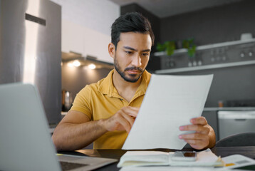 Budget, paperwork and Asian man planning with a laptop for finance, insurance and tax. Payment, note and Japanese entrepreneur reading information on a contract to start a small business from home