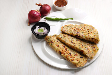 Indian traditional Hot Onion Paratha with tomato chutney. Indian onion stuffed Flatbread. also known as Pyaz ke parathe in Hindi. over a light background with copy space.