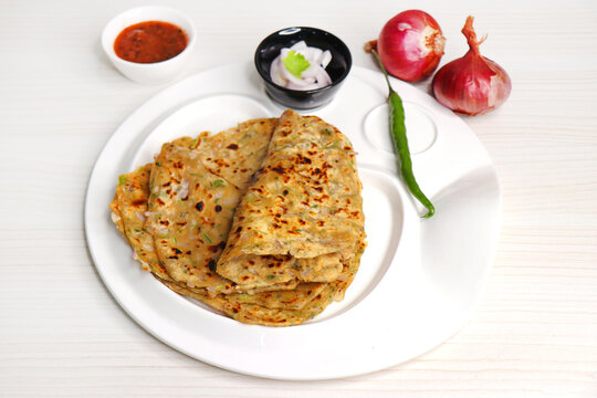 Indian traditional Hot Onion Paratha with tomato chutney. Indian onion stuffed Flatbread. also known as Pyaz ke parathe in Hindi. over a light background with copy space.
