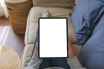 Top view mockup image of a woman holding digital tablet with blank desktop screen on sofa at home