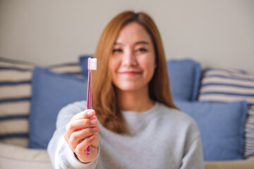 Portrait image of a young woman holding and showing a toothbrush