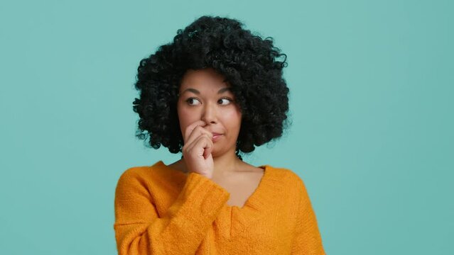 Bewildered confused dark skinned woman with afro hair has doubts and hesitation something. African American girl cant make right decision poses against blue background. Confused Afro American girl 4K