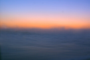 Sunrise horizon over the dark ocean where the sun begins to brighten the sky, retouched and color manipulated image illustration.