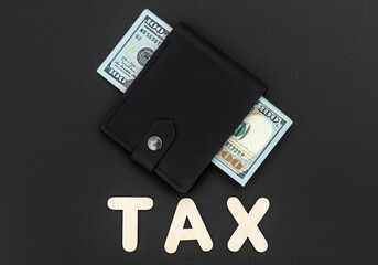 Word "TAX" and wallet with dollar bills on black background. Business and taxation concept. Top view.