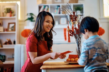Happy Chinese mother giving red envelope to her son for Lunar New Year.