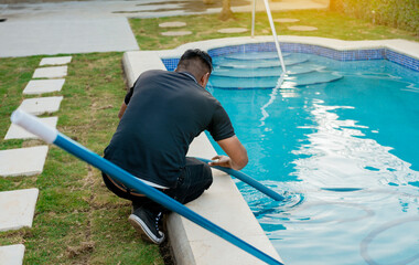 Maintenance person cleaning swimming pool with suction hose. Cleaning and maintenance of swimming...