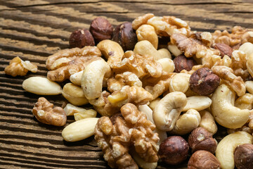 Mix of tasty nuts on a wooden surface. Cashews, almonds, hazelnuts and walnuts on a brown table.