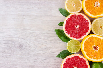 Fototapeta na wymiar Juicy citrus fruits cut background mint leaf. Oranges, lemons, limes, grapefruit, mint leaves on a bright wooden background