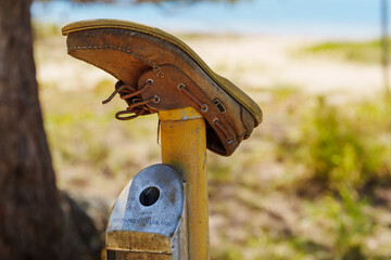 Closeup of single leather boat shoe upside down on a post at the beach. Coochiemudlo Island, Queensland, Australia 