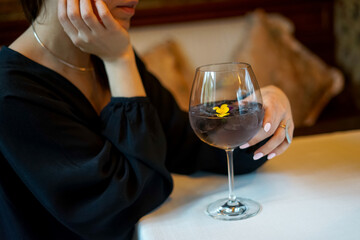 transparent cocktail in a glass decorated with flowers in female hands

