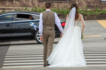 The bride and groom in a wedding dress on a pedestrian crossing.