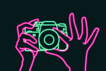 Camera in female hand on dark background. Pink and green neon. Concept art - 563228669