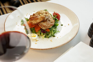 salad with chicken in a plate on the table with a glass of wine
