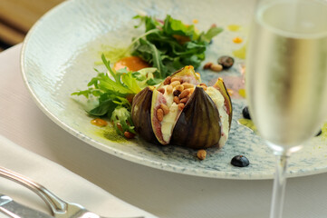 baked figs with cheese sprinkled with nuts in a plate with salad macro
