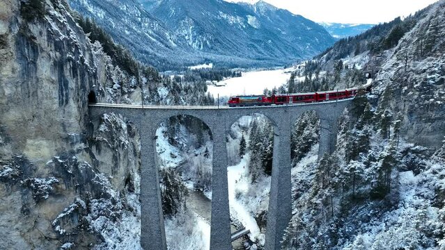 Aerial view of Train passing through famous mountain in Filisur, Switzerland. Landwasser Viaduct world heritage with train express in Swiss Alps snow winter scenery. 
