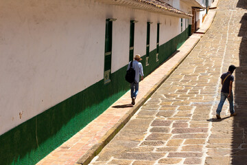 Two men wolking in a typical street with a remarkable stone pavement in Barichara, Colombia.