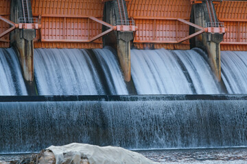 Hydroelectric dam, floodgate with flowing water through gate and open springway at Kew Lom Dam, Lampang, Thailand. Dam