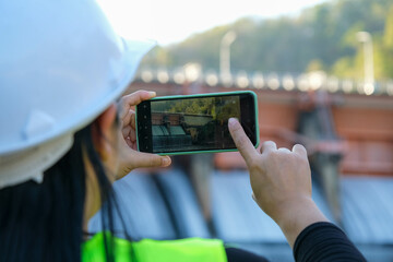 Environmental engineers use mobile phones to take pictures and record data analyzing dam water...