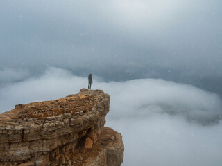 Soft focus. Tourist (woman) stands on the dangerous cliff edge.