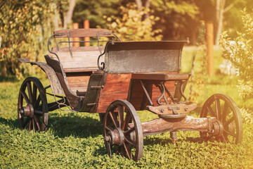 Fototapeta na wymiar Garden Decoration Concept. Decorative Yard Wagon On Summer Lawn. Bright Sunny Day. Gardening And Housekeeping. Vintage Cart On Summer Sunny Day. Garden Wagon. Trolley. Old Wooden Cart.