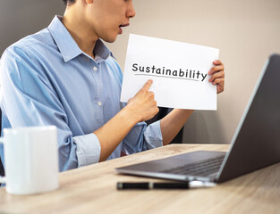 Sustainability on white paper hand holding by asian man making online video meeting - 563232838