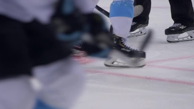 Ice Hockey cinematic slow motion footage of hockey players face off puck. Player Hitting Puck with stick at face off. Stylish Cinematic Close-up, Dramatic Lighting, 1000 fps Slow Motion Shot